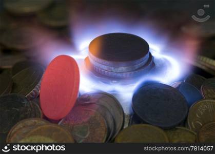 A glowing red hot coin in front of the blue flames of burning natural gas, a metaphor of wasting energy, not only bad for the environment, but also a waste of money