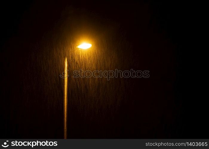 A glowing street lamp at rainy night.