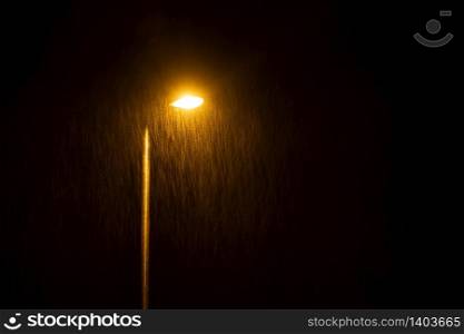 A glowing street lamp at rainy night.