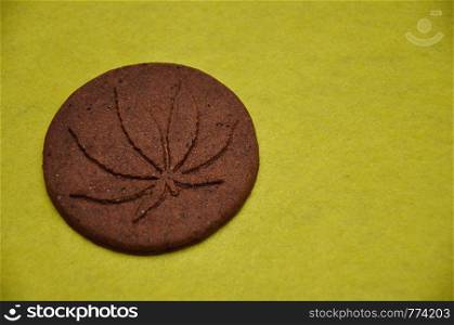A golden brown cannabis biscuit with a cannabis leave print
