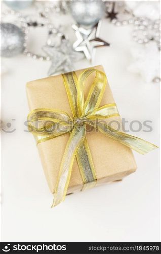 A golden gift box stands in the center of the frame, created from craft paper on a white background. View from above. Present time. A golden gift box stands in the center of the frame, created from craft paper on a white background. View from above. Present time.