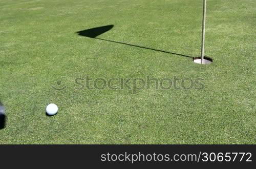 a golfer makes his hit, ball runs in hole