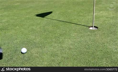 a golfer makes his hit, ball runs in hole