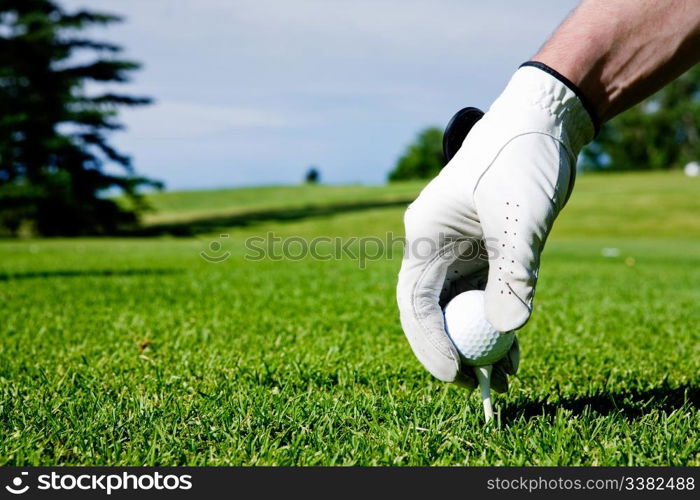 A golfer sets up a tee at a driving range