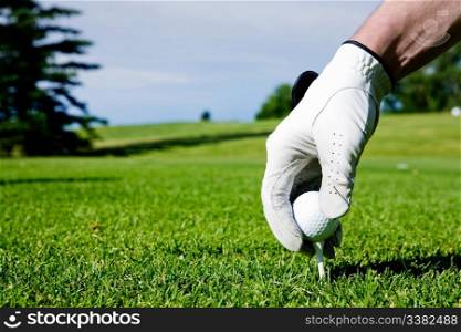A golfer sets up a tee at a driving range