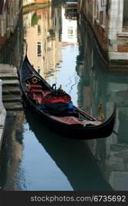 A gondolar moored beside a set of stairs on a canal, Venice, Italy