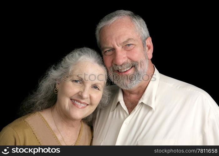 A good looking silver haired mature couple over a black background.