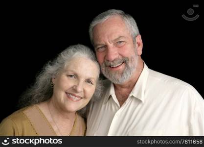 A good looking silver haired mature couple over a black background.