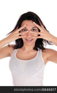 A gorgeous Hispanic woman in a white t-shirt holding her hands overher face and looking through the finger, isolated for white background.. Young woman looking through her fingers.