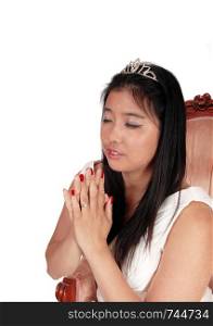 A gorgeous young Asian woman siting in a white dress with long black hair, praying, with her hands folded, isolated for white background