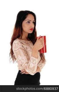 A gorgeous young business woman in a beige blouse and black skirtholding a red big coffee mug, looking serious, over white background