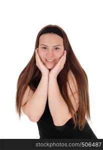 A gorgeous young teenager girl in a black swatter holding booths hands on her face and smiling, isolated for white background