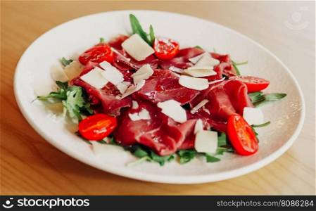A gourmet dish of beef carpaccio and Parmesan cheese