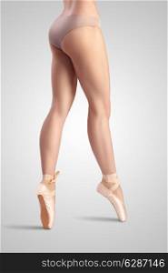 A graceful female classical ballet dancer on pointe shoes wearing beige satin underwear and standing on toes on a neutral light studio background.