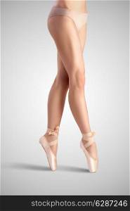 A graceful female classical ballet dancer on pointe shoes wearing beige satin underwear and standing on toes on a neutral light studio background.