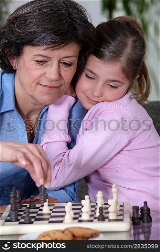 A grandmother and her granddaughter playing chess.