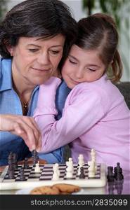 A grandmother and her granddaughter playing chess.