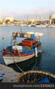 A Greek fishing caique (kaiki) with a long-line basket, hooks planted all round its rim, in the foreground. A common sight in the Greek islands, this was shot in Heraklion, Crete. The focus is on the boat.