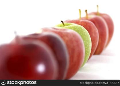 A green apple is the odd one out in a line of red