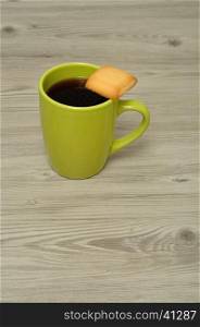 A green coffee mug with a biscuit balanced on top