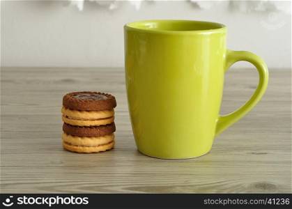 A green coffee mug with a stack of round biscuits