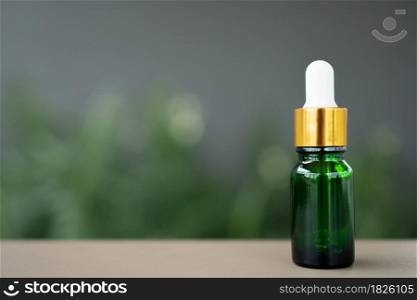 A green glass bottle with dropper on the table. Concept of aroma oil, cosmetic, and beauty skin.
