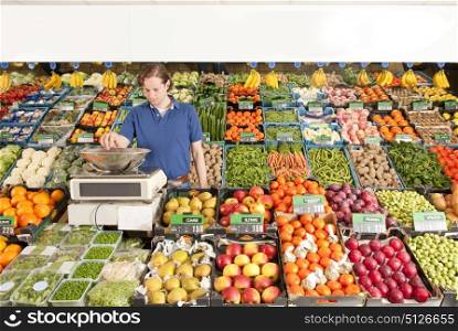 A green grocer weighing vegetables in a grocery shop