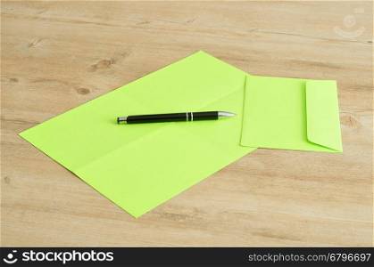 A green paper and envelope with a pen