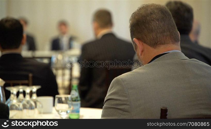 A grey suited man attends a lecture