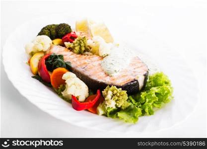 A grilled salmon steak with vegatable and lemon sauce
