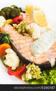 A grilled salmon steak with vegatable and lemon sauce