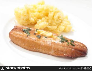 A grilled smoked herring or kipper, garnished with herbs and a dab of butter, served with mashed boiled potatoes