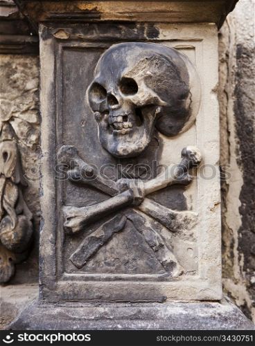 A grisly image of death grimacing with a skull and crossbones on a headstone in Kylemore Abbey in Edinburgh, Scotland.