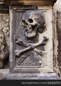 A grisly image of death grimacing with a skull and crossbones on a headstone in Kylemore Abbey in Edinburgh, Scotland.