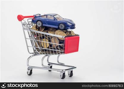 A grocery shopping cart filled with coins and a car on top