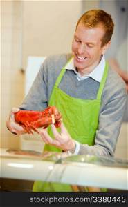 A grocery store worker with a lobster at the fish counter