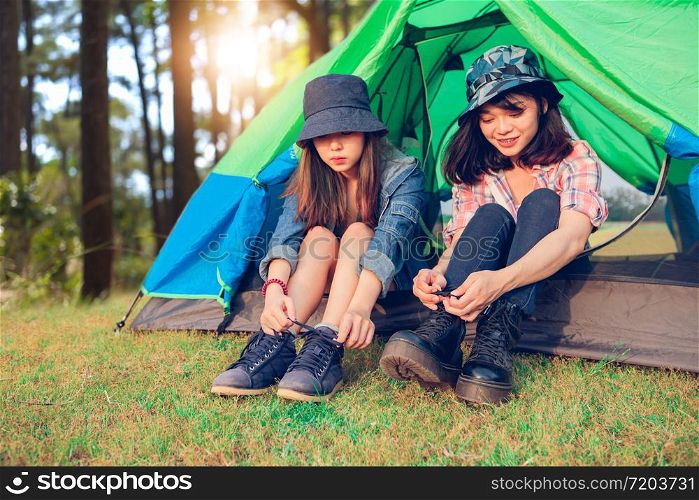 A group of Asian friends tourist Tie a shoe near tent with happiness in Summer while having camping