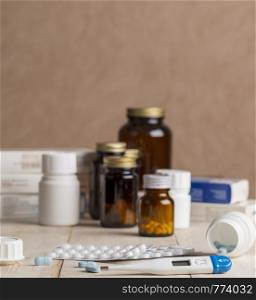 A group of boxes of medicines, pill bottles, thermometer and blisters of pills on wooden table. A group of boxes of medicines, pill bottles, thermometer and blisters of pills