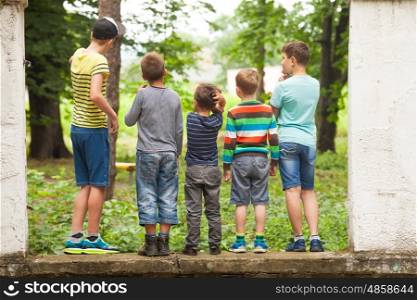 A group of boys looking at a tree in the park back view. Group of guys in a row back view