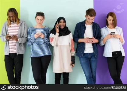 a group of diverse teenagers use mobile devices while posing for studio photography 