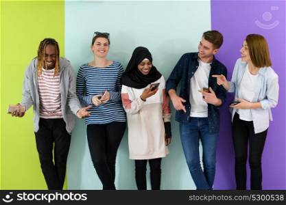 a group of diverse teenagers use mobile devices while posing for studio photography
