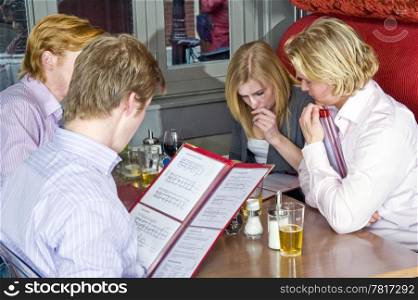 a group of four people chosing dishes from the menu in a restaurant