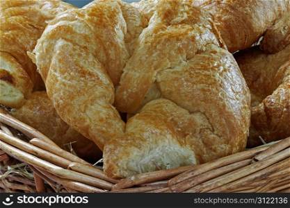 A group of fresh croissants in a hay filled basket