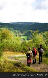 A group of hikers enjoying the view over the Ardennes mountains in the late summer.