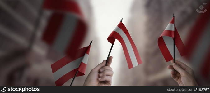 A group of people holding small flags of the Austria in their hands.. A group of people holding small flags of the Austria in their hands