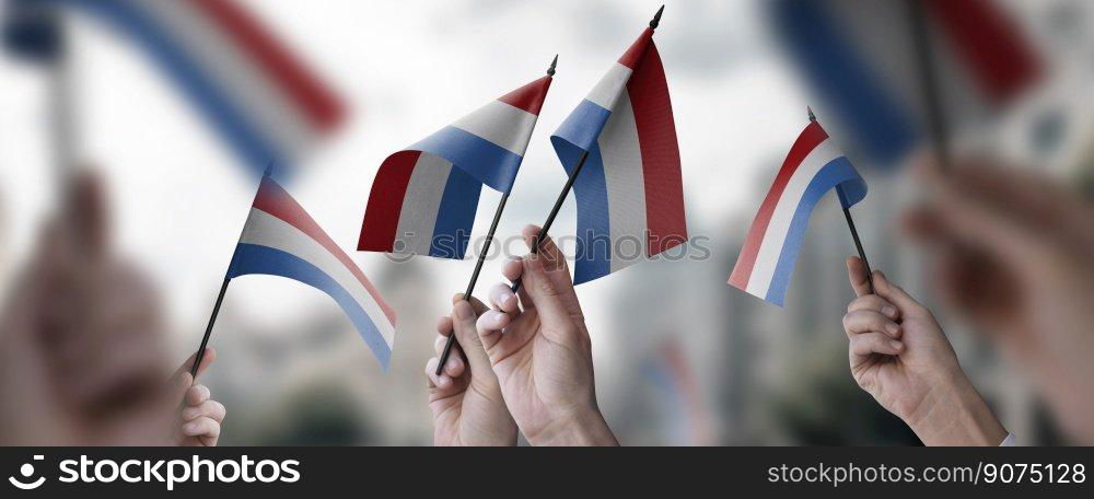 A group of people holding small flags of the Netherlands in their hands.. A group of people holding small flags of the Netherlands in their hands