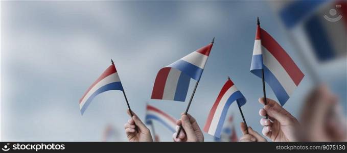 A group of people holding small flags of the Netherlands in their hands.. A group of people holding small flags of the Netherlands in their hands