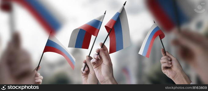 A group of people holding small flags of the Russia in their hands.. A group of people holding small flags of the Russia in their hands