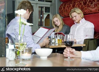 A group of people looking at the menu in a restaurant