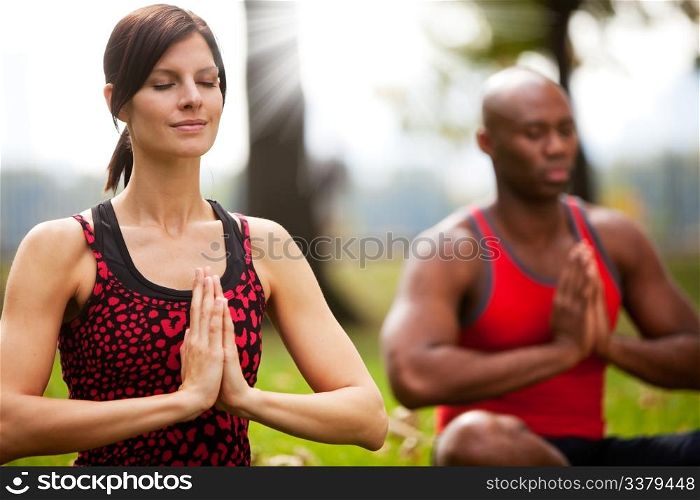 A group of people peacefully meditating in a park
